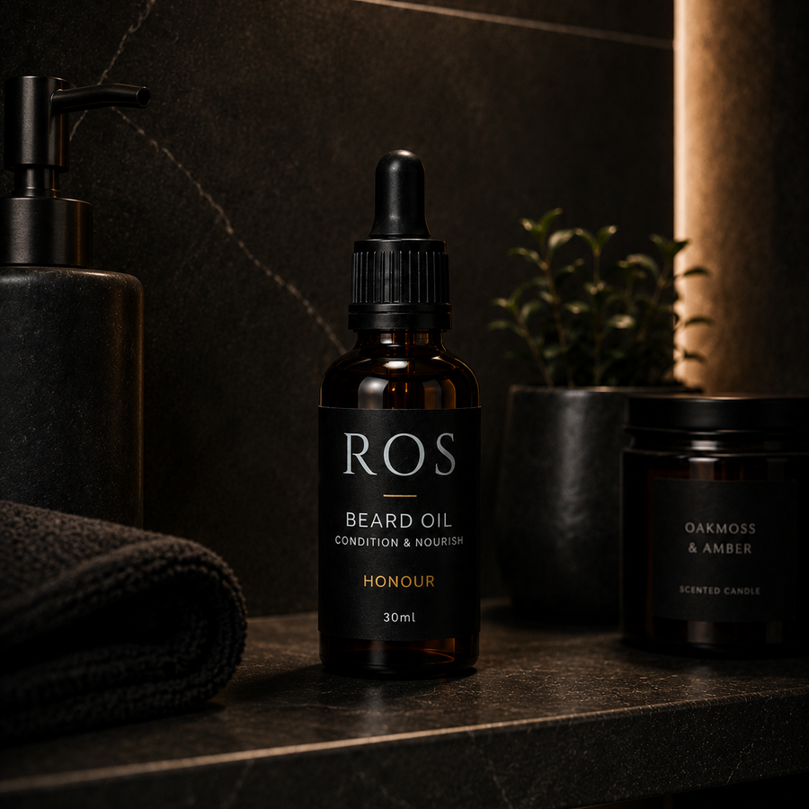 Beard oil bottle labeled 'ROS' on a dark surface with a towel and plant in the background.