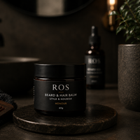 Black jar of ROS Beard & Hair Balm on a dark surface with a blurred background
